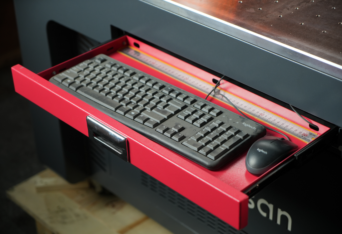 Выдвижной красный лоток под рабочей зоной лазерного маркера Wattsan GT с размещенной клавиатурой и мышью Logitech для оператора.